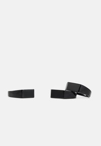 Anéis de resina preta com uma forma retangular elegante e acabamento brilhante. Dois anéis estão na posição vertical, um está empilhado com uma ligeira sobreposição.