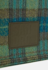 Tissu à carreaux en bleu, vert et gris avec une finition texturée. Comprend une étiquette rectangulaire en cuir embossée du texte "SANDRO PARIS."