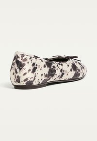 Damen Ballerinas mit schwarz-weißer gepunkteter Musterung und einer kleinen Schleife oben, von der Seite und von hinten gezeigt.