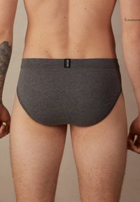 Grijze katoenen slip met een gladde textuur, lage taille en een klein etiket op de achterste tailleband. Geen zichtbare patronen of accenten.