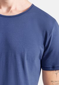 Granatowa, krótkosleeve koszulka z miękkiego materiału, z okrągłym dekoltem, minimalistycznym przeszyciem oraz gładką teksturą.