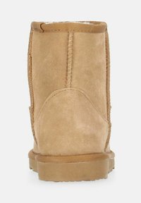 Tan-farbene Wildleder-Ankle-Boots mit abgerundeter Form, genähten Nähten und einer flachen Gummisohle. Das Innere ist mit weichem Material ausgekleidet, um Wärme zu bieten.