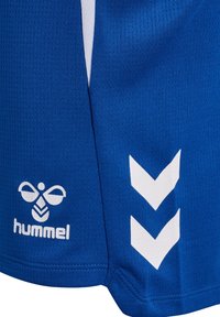 Niebieska sportowa tkanina z białym logo hummel i dwoma białymi paskami w kształcie jaskółki na szwie bocznym.