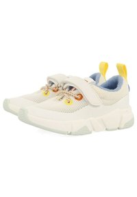 Zapatillas de malla ligeras en blanco roto con acentos en amarillo y azul. Cuentan con una correa de Velcro, suela texturizada y cordones decorativos.