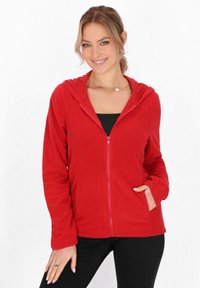 Hanorac din fleece roșu, cu glugă, fermoar pe toată lungimea frontală și buzunare laterale. Textură moale și mâneci lungi, cu o croială lejeră.