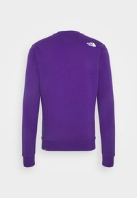 Fialová mikina s dlouhými rukávy, žebrovanými manžetami a lemem a kulatým výstřihem. Na horní části zad je malý bílý logo.