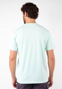 Camiseta de manga corta verde menta en suave tejido de algodón. Cuello redondo simple y textura lisa. Sin patrones ni logotipos visibles.