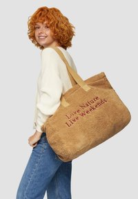 Torebka tote w kolorze tan, miękka w dotyku, z napisem „Kochaj naturę, żyj weekendem” w kolorze burgundowym. Posiada dwa mocne, jasne uchwyty.