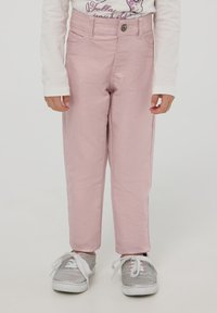 Jasnoróżowe dżinsy o prostym kroju, z przodem zapinanym na guzik, z detalami kieszeni i jasnym przeszyciem, w połączeniu z srebrnymi sneakersami.