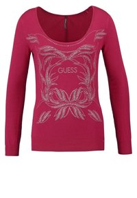 Maglione fucsia a maniche lunghe con scollatura a girocollo, caratterizzato da un design floreale decorato con embellishments argentati e il logo "GUESS" sul petto. Tessuto in maglia testurizzata.