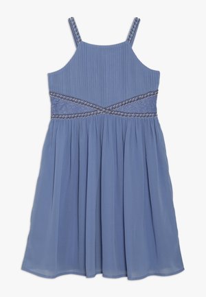 Robe bleue sans manches avec corsage plissé, ceinture croisée perlée et jupe fluide sur fond blanc.