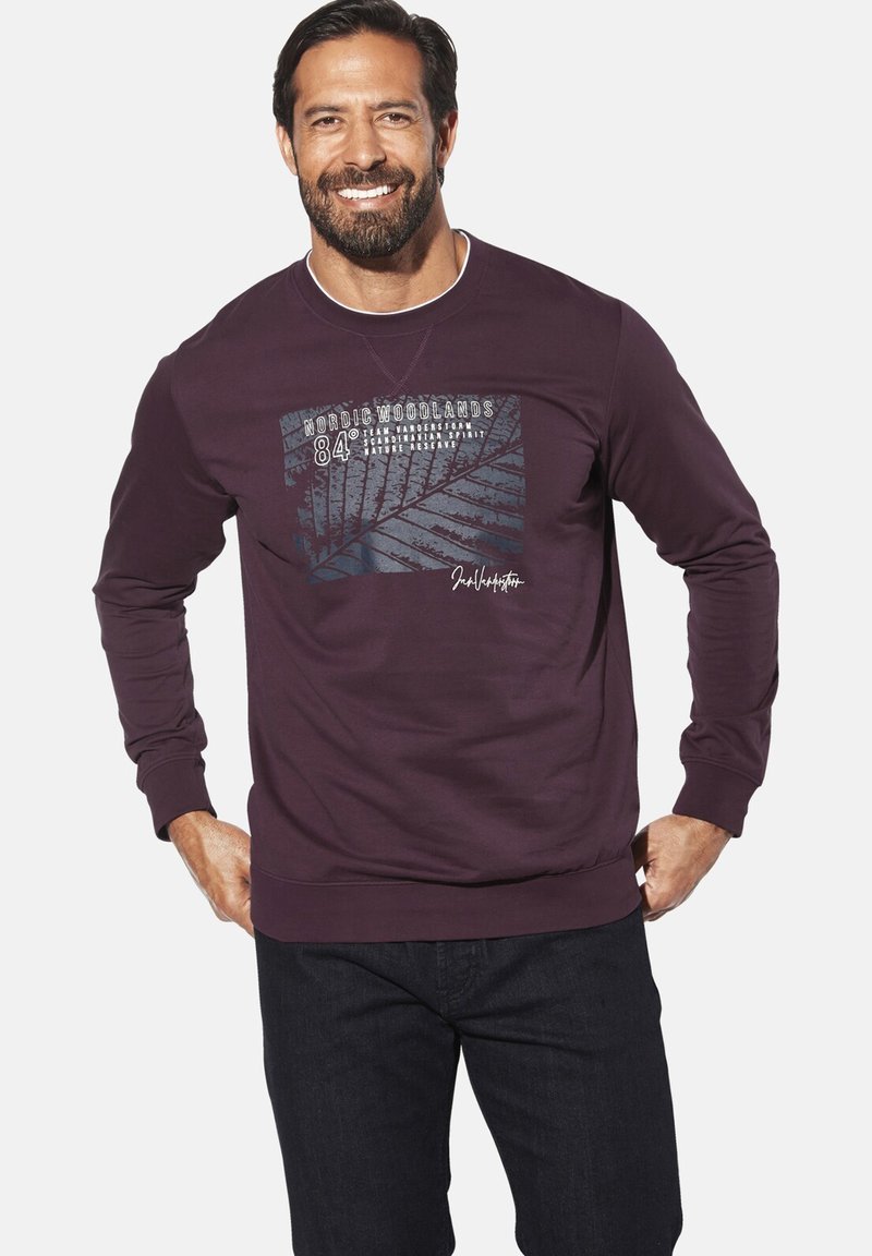 Maroon sweatshirt with long sleeves, graphic print featuring foliage and text, round neck, ribbed cuffs and hem. Dark jeans worn underneath.