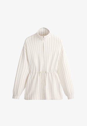 Veste blanche à fermeture éclair, avec fines rayures noires verticales, manches longues, col montant et taille ajustable avec cordon de serrage.