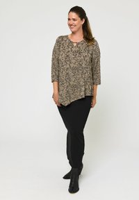 Beige mintás felső háromnegyedes ujjal, kulcslyuk részlettel. Fekete, bokáig érő szoknyával és fekete bokacsizmával párosítva.