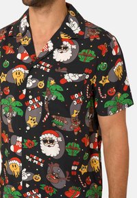 Camicia a maniche corte con un motivo festivo multicolore che presenta Babbo Natale, regali e motivi natalizi su uno sfondo nero.