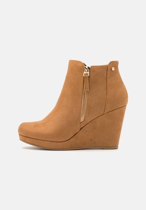 Botins de camurça tão em tom caramelo com salto em cunha, fecho lateral, ponta arredondada e superfície texturizada. Apresenta um fecho de zíper em tom dourado e um acento de hardware decorativo.