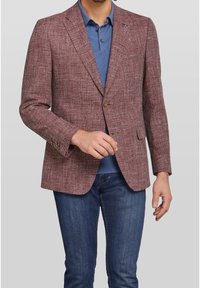 Blazer texturizzato bordeaux con chiusura a due bottoni, taschino sul petto e rever a notched, indossato sopra un polo blu e abbinato a jeans scuri.