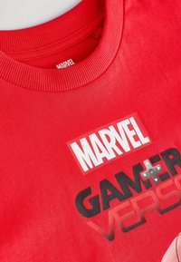 Červené bavlněné tričko s žebrovaným kulatým výstřihem, potiskem loga "MARVEL" a textem "GAMER VERSUS" spolu se stvárněním herního ovladače.