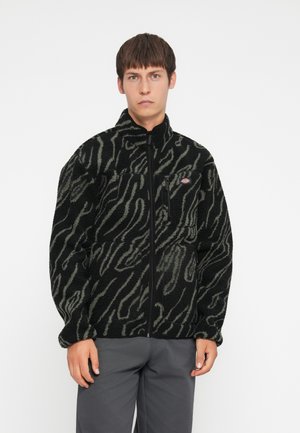 Black fleece jacket with gray zebra stripes, full zip front, high collar, and zippered chest pocket. Soft texture and relaxed fit.