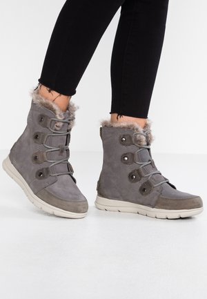 Grå ruskinds ankelstøvler med faux fur kant, der har seks snørehuller med snørebånd og en tekstureret gummisål for bedre greb.
