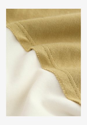 Pamut anyag, amely megosztott dizájnnal rendelkezik, texturált khaki és sima fehér szakaszokkal, kiemelve a kontrasztos színeket és varrási részleteket.