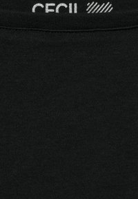 Zwarte katoenen T-shirtstof met een gladde textuur. Heeft een label met de merknaam "CECIL" in zilver, geplaatst bij de halslijn.
