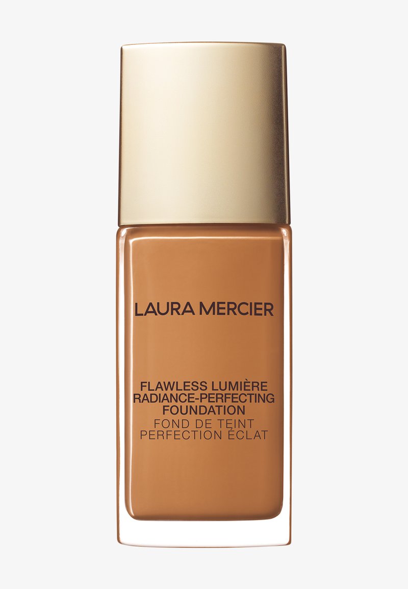 Laura Mercier-foundation i en klar glassflaske med et gyldent lokk, inneholder en glatt ravfarget væske og svart tekst som merker produktet.