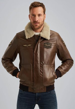 Brown leather bomber jacket with a faux fur collar, featuring two front pockets, embroidered patches, and ribbed cuffs and hem.