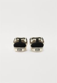 Sorte ruskind og mønstrede stof sneakers med kontrasterende cremefarvede mellemsåler, der har polstrede kraver og Vans-logo på hælen.