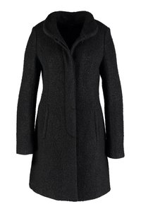 Cappotto in misto lana nero, lungo fino al ginocchio, con colletto alto, maniche lunghe e tasche laterali, realizzato in un tessuto bouclè strutturato.