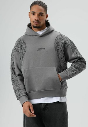 Grijze hoodie met grafisch zwart patroon op de mouwen, buidelzak en tekstdetail. Capuchonmodel met geribbelde boorden en zoom. Zachte stofstructuur.