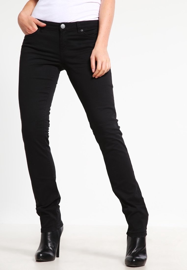Jeans ajustados negros con una textura suave, diseño de cinco bolsillos y botón plateado en contraste. Combinados con botas altas negras de tacón.