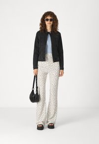 Melna denim jaka, gaiši zils tops, baltas bikses ar melniem punktiņiem, melna rokassoma un masīvas melnas platformas kurpes. Četrkārtīgi mati un saulesbrilles.