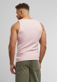 Lyserød bomulds tanktop med ribbet tekstur, med rund halsudskæring og tætsiddende silhuet, parret med olivengrønne shorts.