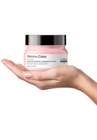 Rosa burk med L'Oréal Professionnel Vitamin Color mask, med ett svart lock, handstor för enkel hantering, märkt för vård av färgat hår.