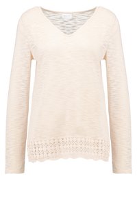 Långärmad krämfärgad topp med V-ringning, texturerad kropp och spetsdekoration vid nederkanten, med ett fint scallopmönster.