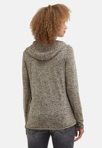 Grau mit Kapuze versehenes Sweatshirt mit einem strukturierten, unregelmäßigen Muster. Hergestellt aus einem weichen, elastischen Material. Verfügt über lange Ärmel und einen abgerundeten Saum.