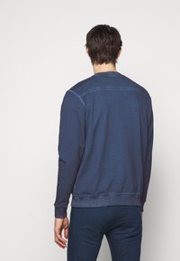Felpa blu navy realizzata in morbido tessuto, con collo rotondo e polsini a costine. Texture sottile con dettaglio cucito sul retro.