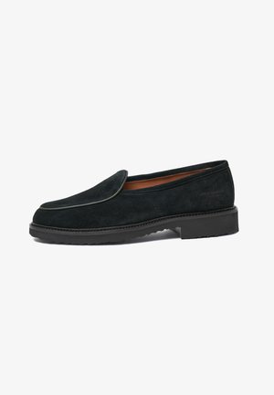 Sorte ruskinds loafers med rund tå, kontrasterende piping og en struktureret gummisål. Har et minimalistisk design og flad hæl.