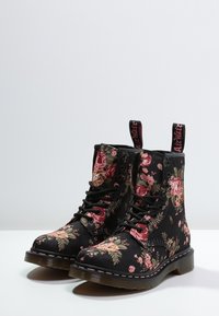 Czarne kwieciste botki bojowe z tkaniny z różowymi różami, sznurówkami oraz masywną podeszwą o teksturowym wykończeniu i różowymi przeszyciami.