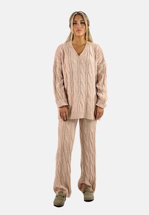 Conjunto de loungewear de punto en rosa claro. Presenta un suéter holgado con escote en V y patrón de trenzas, junto con pantalones a juego con un diseño texturizado y puños.