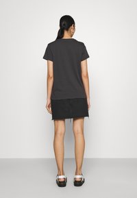 Tmavě šedé bavlněné tričko s krátkými rukávy, doplněné černou džínovou sukní s ošoupaným lemem. Oblečení doplněné o pohodlnou obuv.