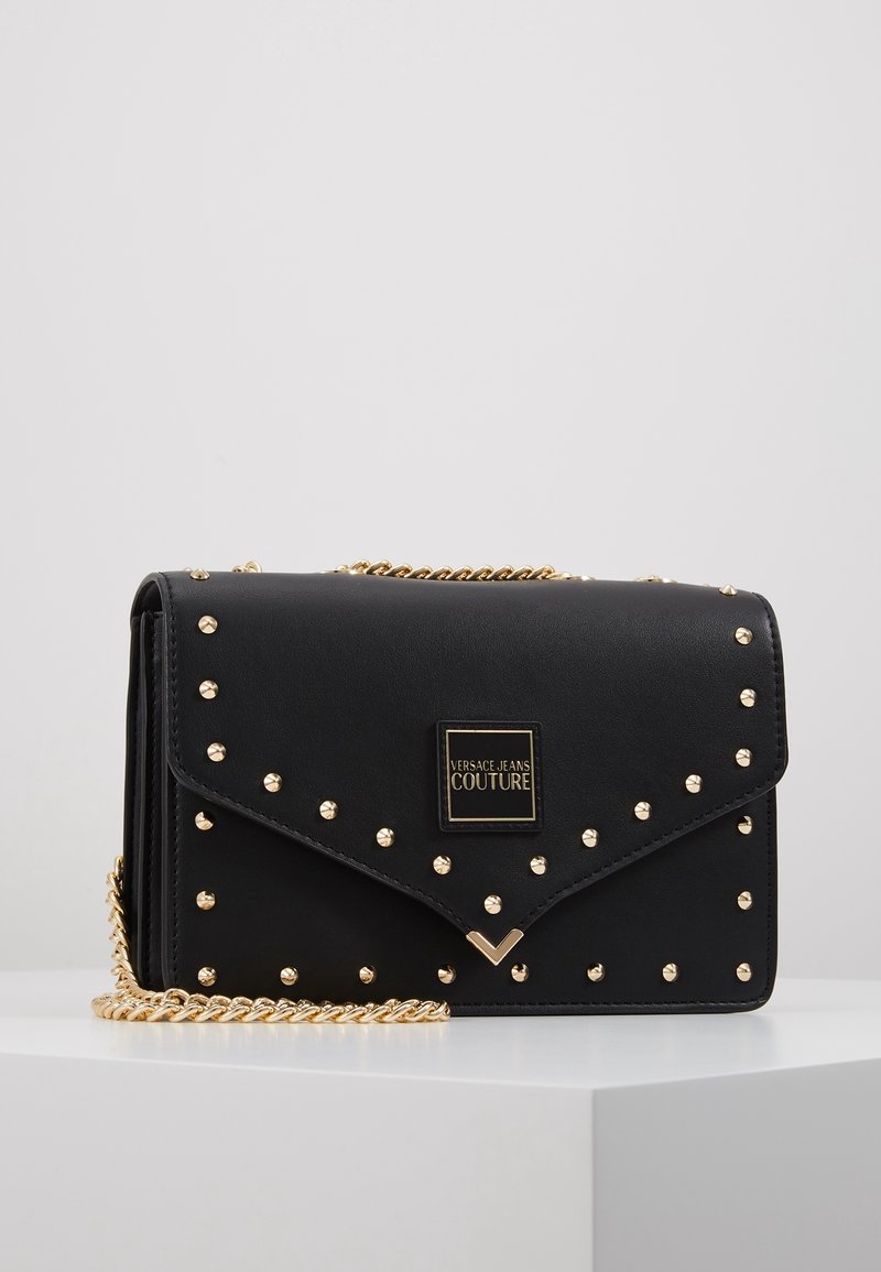 Borsa a spalla in pelle nera con dettagli in oro, tracolla a catena e chiusura magnetica. Presenta una placca con il logo del marchio sul davanti.