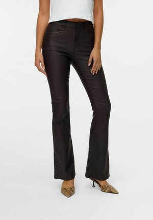 Pantalons évasés noirs avec une texture lisse et une taille haute. Portés avec des talons à bout pointu à motifs.