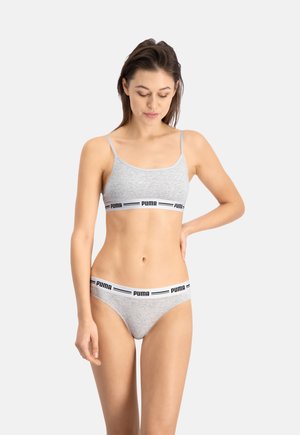 Bralette en coton gris avec des bretelles fines et une bande logo noir et blanc ; culottes en coton gris assorties avec une bande logo similaire.