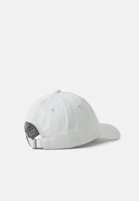Lys grå baseballcaps med justerbart bånd og metalspænde, vist på en hvid baggrund vendt mod venstre.