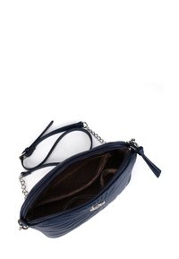 Tmavě modrá kožená crossbody taška s prošívanou texturou, zipovým uzávěrem, řetízkem na nošení a vnitřní kapsou s hnědým puntíkovaným podšíváním.