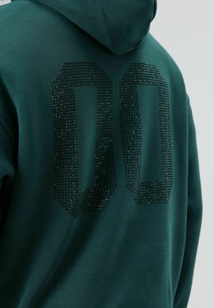 Sweat à capuche vert avec un grand design "00" orné de diamants au dos. Tissu doux, coupe décontractée et capuche ajustable.
