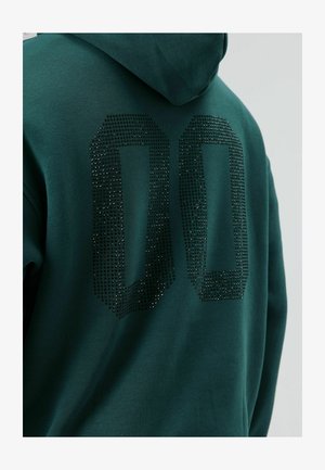 Sweat à capuche vert avec un grand design "00" orné de diamants au dos. Tissu doux, coupe décontractée et capuche ajustable.