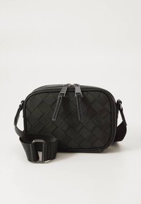 Crna tkanina torba preko tijela pravokutnog oblika, zatvaranje na patentni zatvarač, podesivi remen i elegantni metalni detalji.